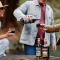 Three friends in the forest pouring Brucato Amaro cocktails and laughing.