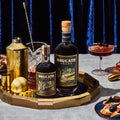 Brucato Amaro Woodlands bottles, cocktails, and food on a decorated table.